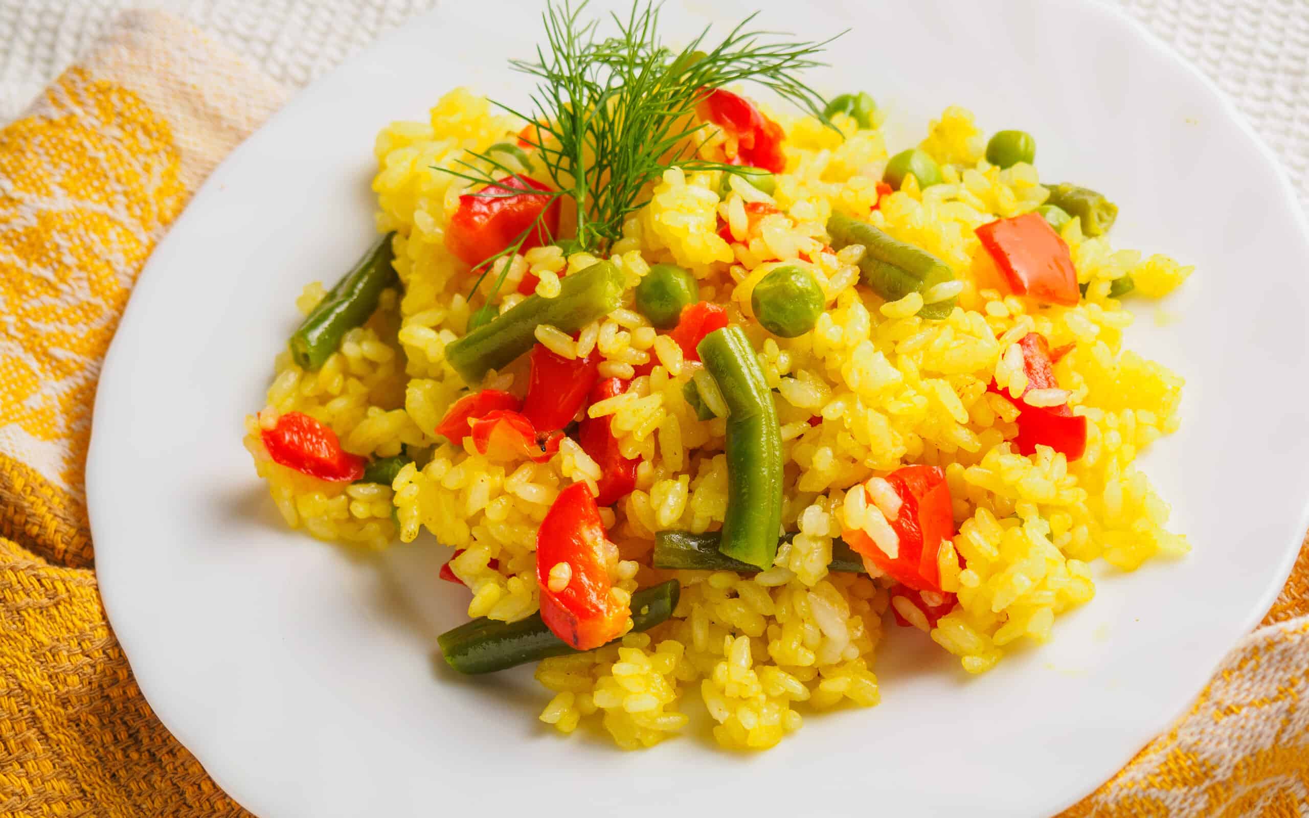 pilaf with meat with greens on a white plate.