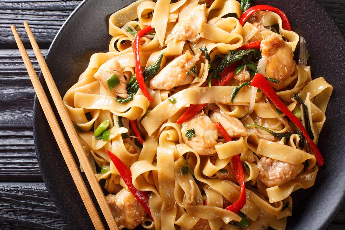 pad kee mao rice noodles with chicken, basil, chili pepper and sauce close-up on a plate on the table. horizontal top view from above