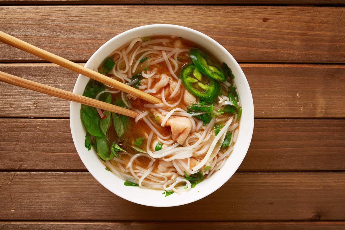 eating a bowl of vietnamese beef pho with chopsticks shot top down