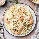 Italian pasta fettuccine in a creamy sauce with shrimp on a plate, top view