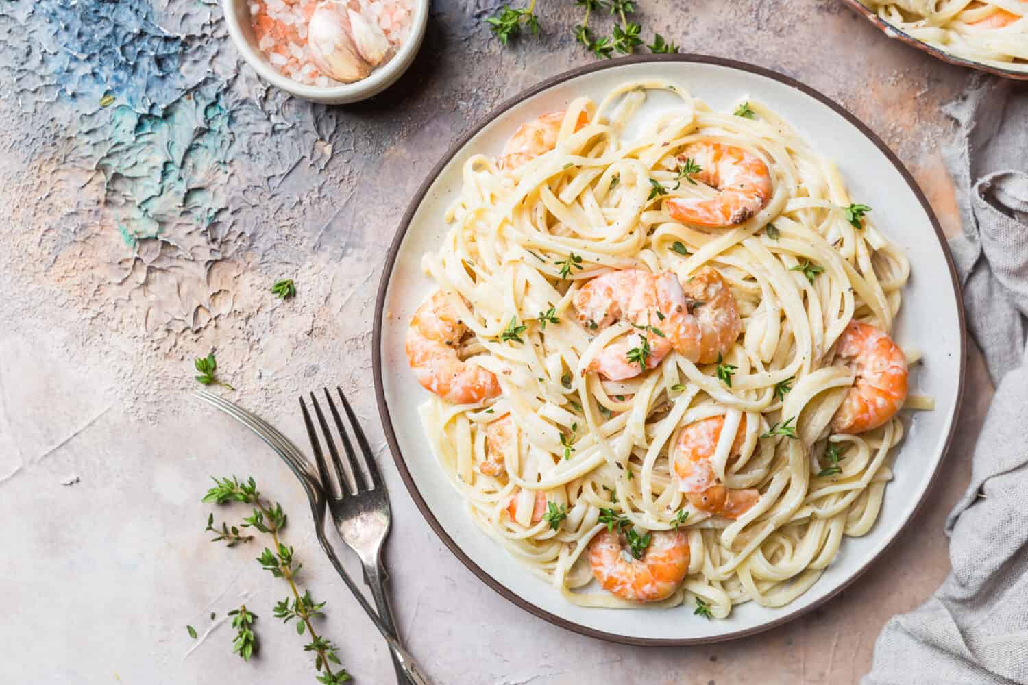 Italian pasta fettuccine in a creamy sauce with shrimp on a plate, top view