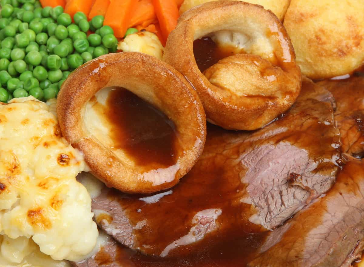 Traditional Sunday roast beef dinner with Yorkshire puddings and gravy.