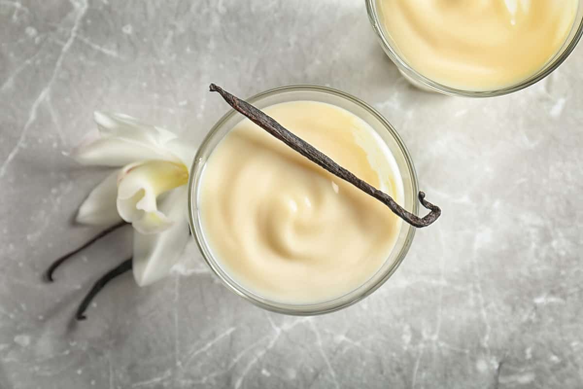 Vanilla pudding, sticks and flower on light background