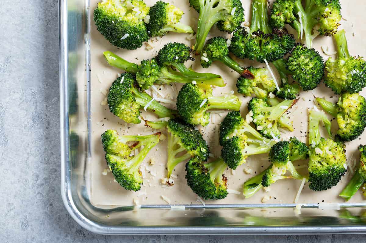 Roasted broccoli florets with cheese on a baking tray