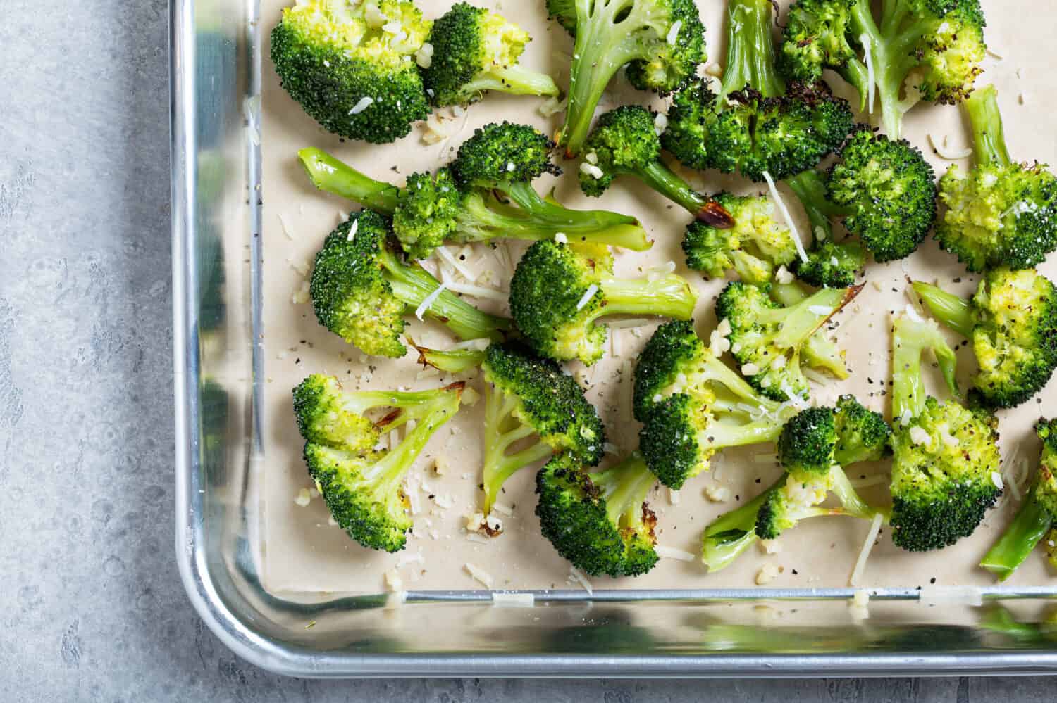 Roasted broccoli florets with cheese on a baking tray