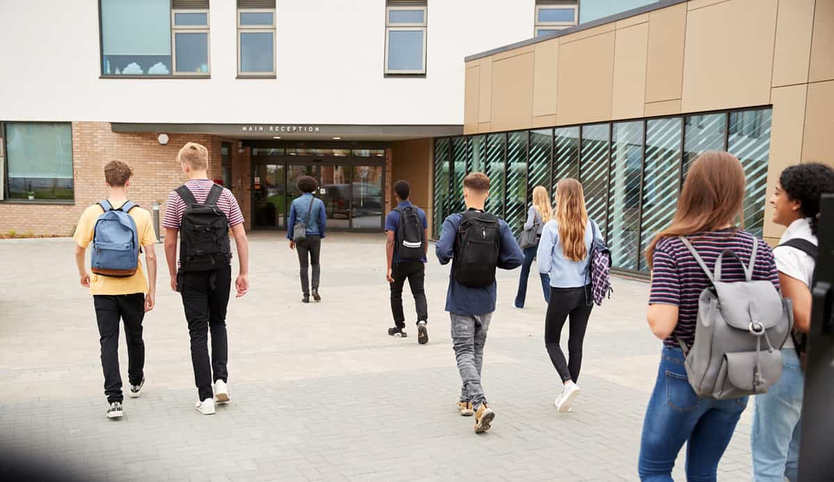 Rear View of High School Students Walking Into College Building Together