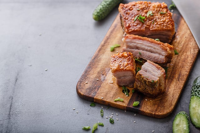 Chinese roasted pork belly on wooden cutting board copy space.