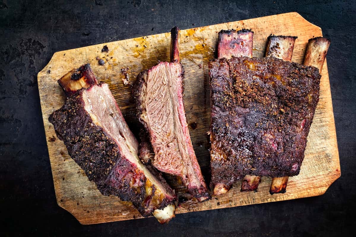 Barbecue chuck beef ribs with hot rub as top view sliced on a wooden cutting board