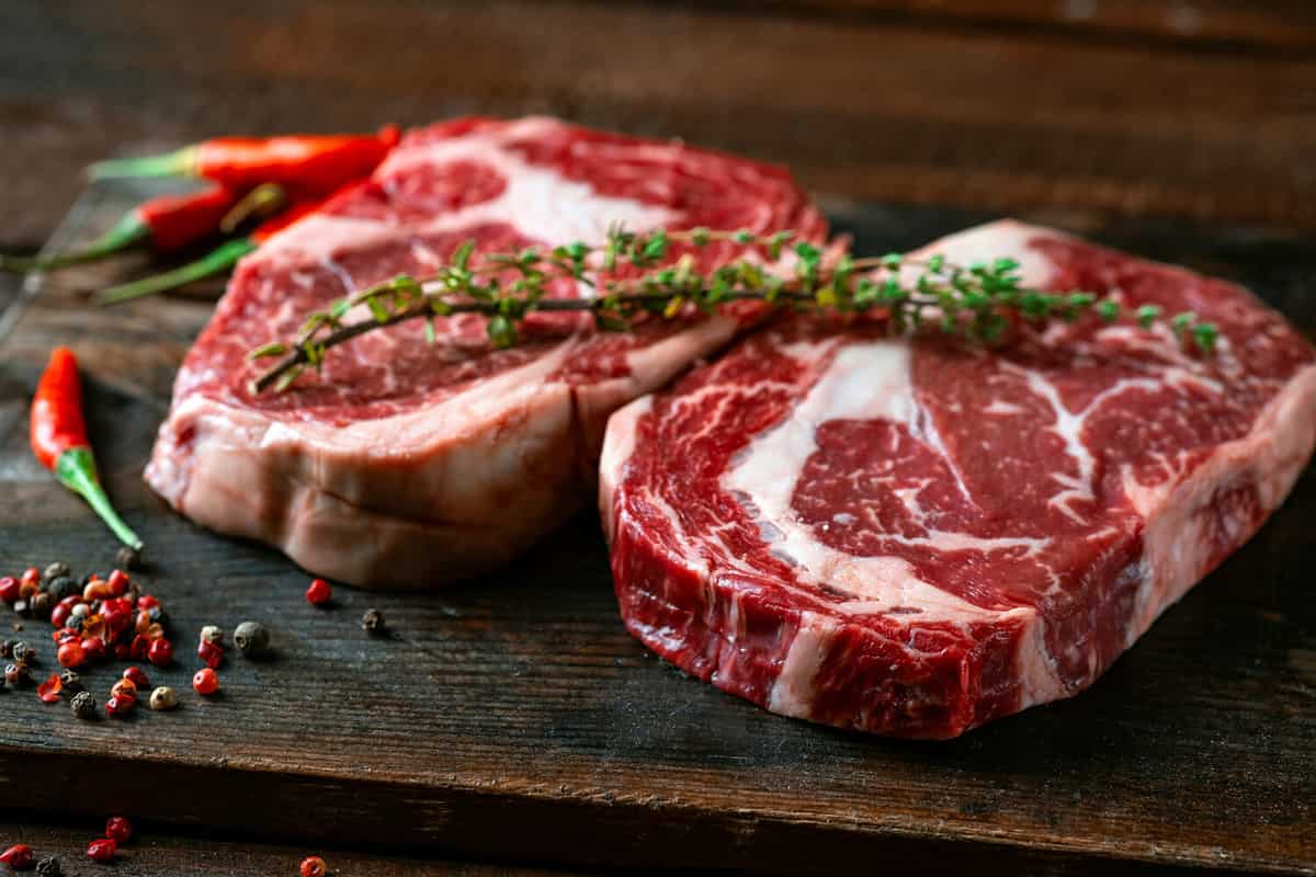 Two classic fresh rib eye steaks on a wooden Board