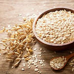 oatmeal flakes and ears of oat on wooden table