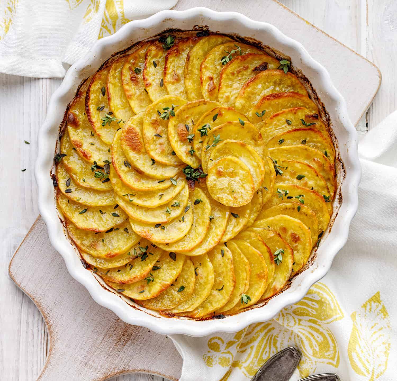 Scalloped potatoes, potato casserole with the addition of aromatic herbs  in a ceramic baking dish, top view