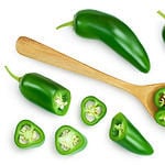 sliced jalapeno pepper in wooden bowl isolated on white background. Green chili pepper with clipping path. Top view. Flat lay