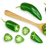 sliced jalapeno pepper in wooden bowl isolated on white background. Green chili pepper with clipping path. Top view. Flat lay