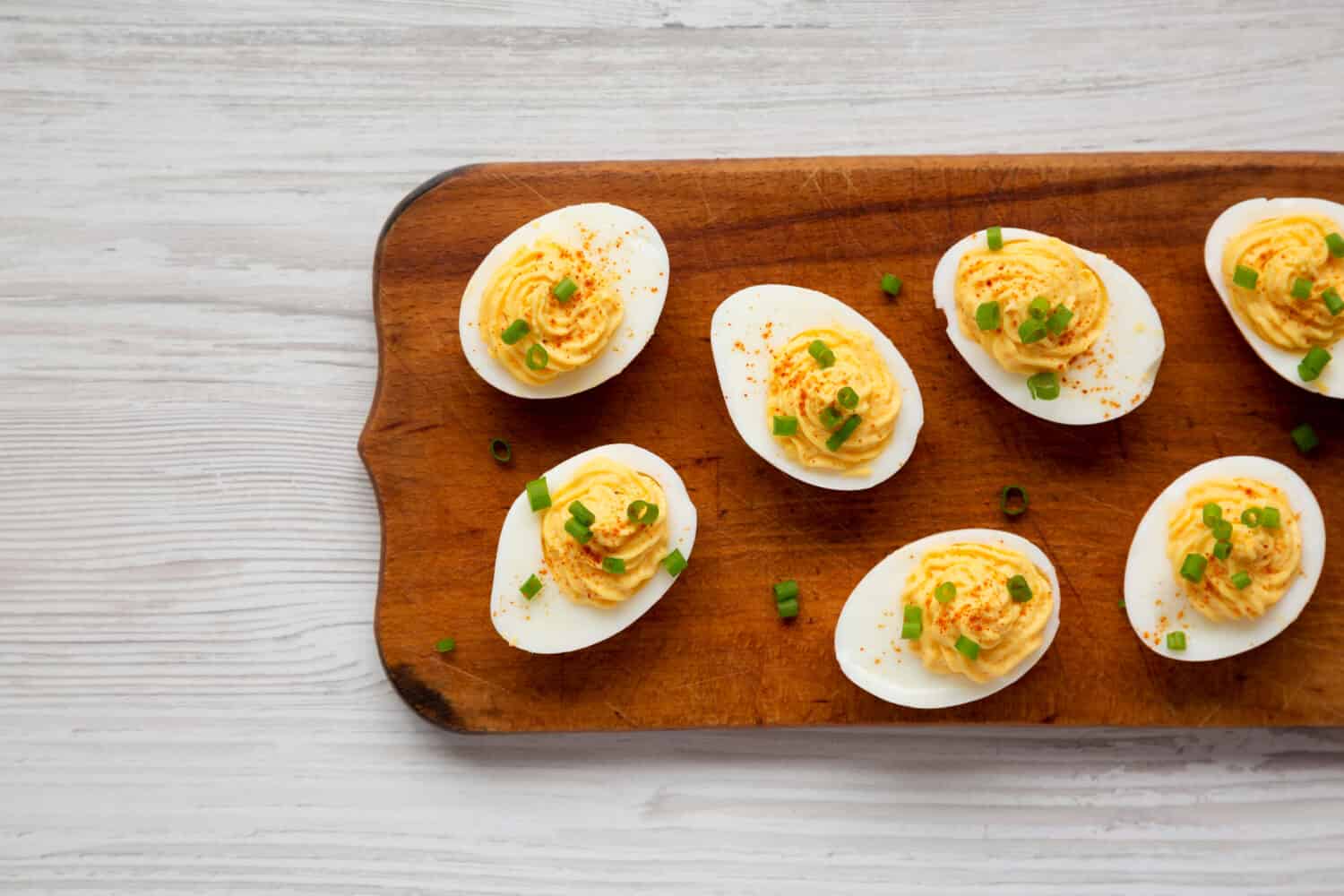 Homemade Deviled Eggs with Chives on a rustic wooden board, view from above. Flat lay, top view, overhead.