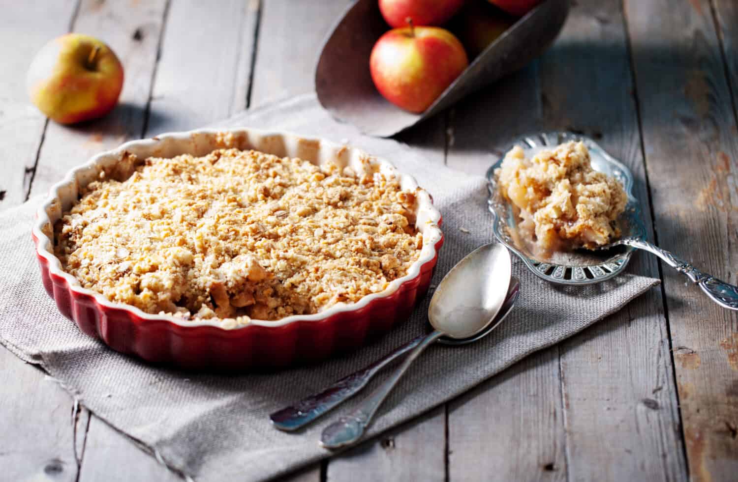 Apple crumble on the wooden background with apples .