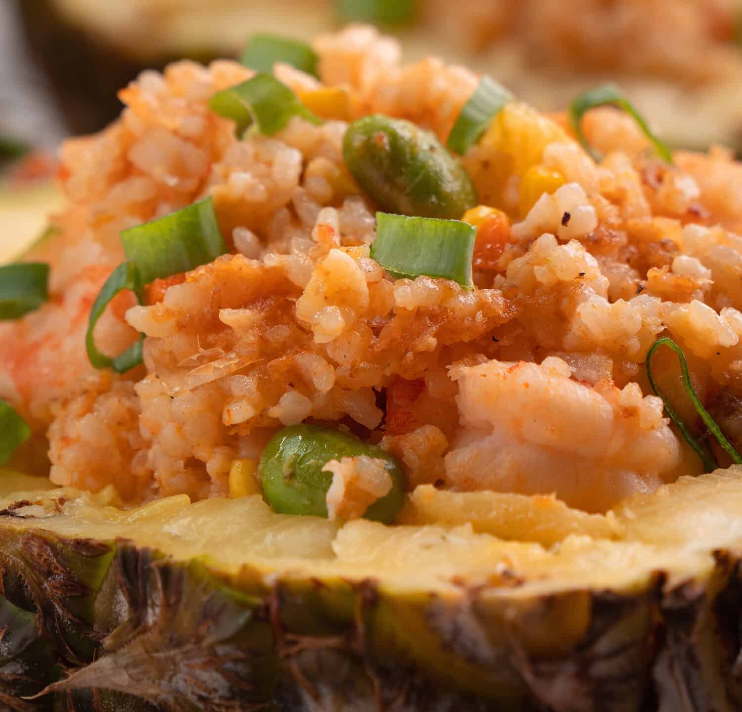 Delicious carved pineapple served as a bowl container boat stuffed with fresh pineapple tomato sauced seafood fried rice.