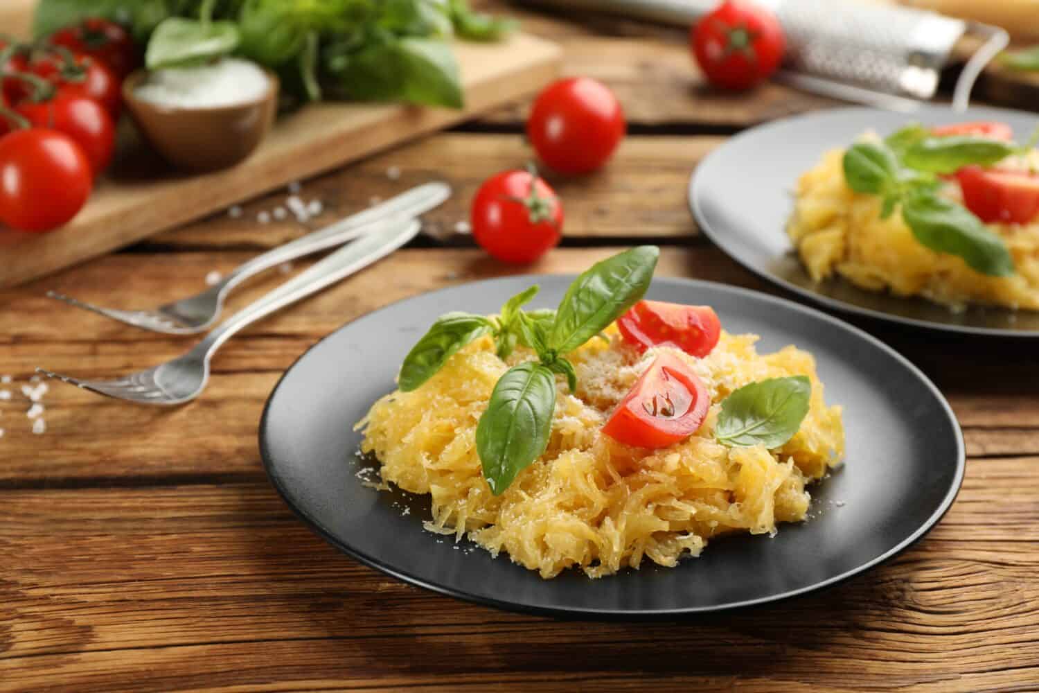 Tasty spaghetti squash with tomatoes and basil served on wooden table