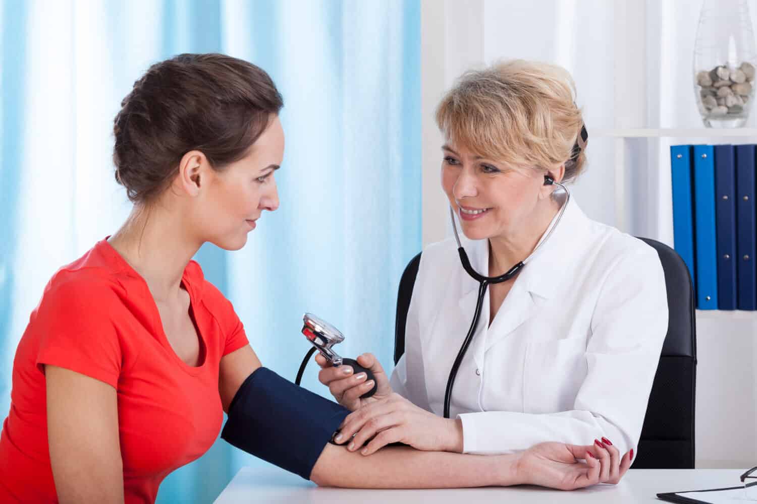 The doctor measures the pressure of a young woman