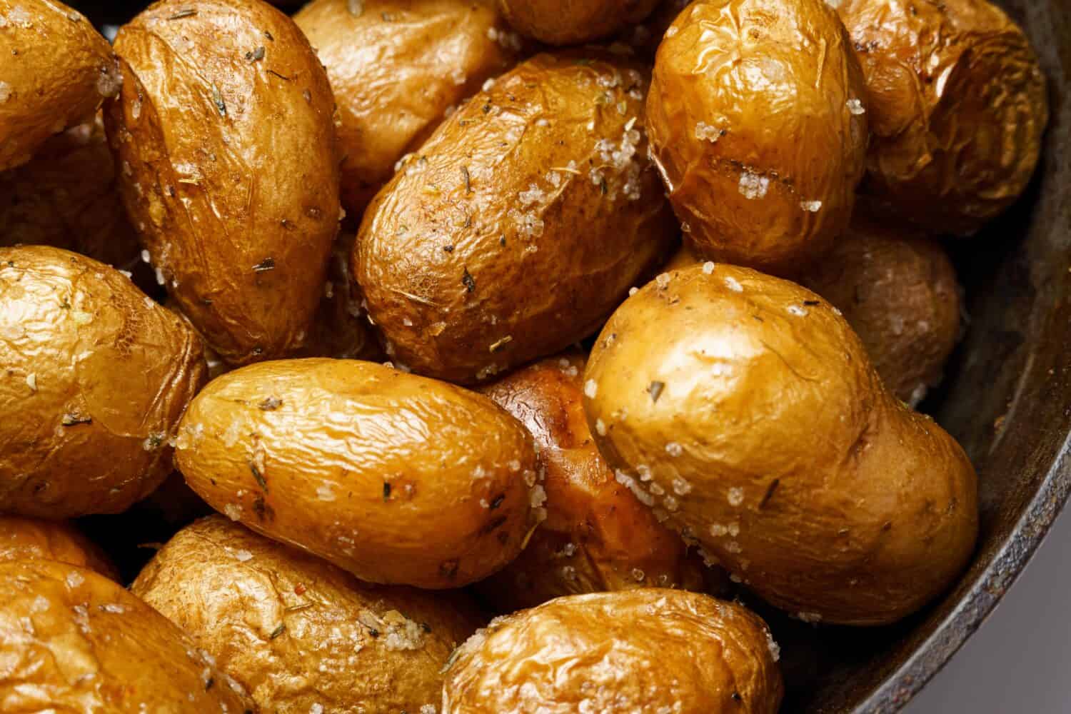 roasted potatoes in a frying pan closeup, whole cooked food, delicious crust