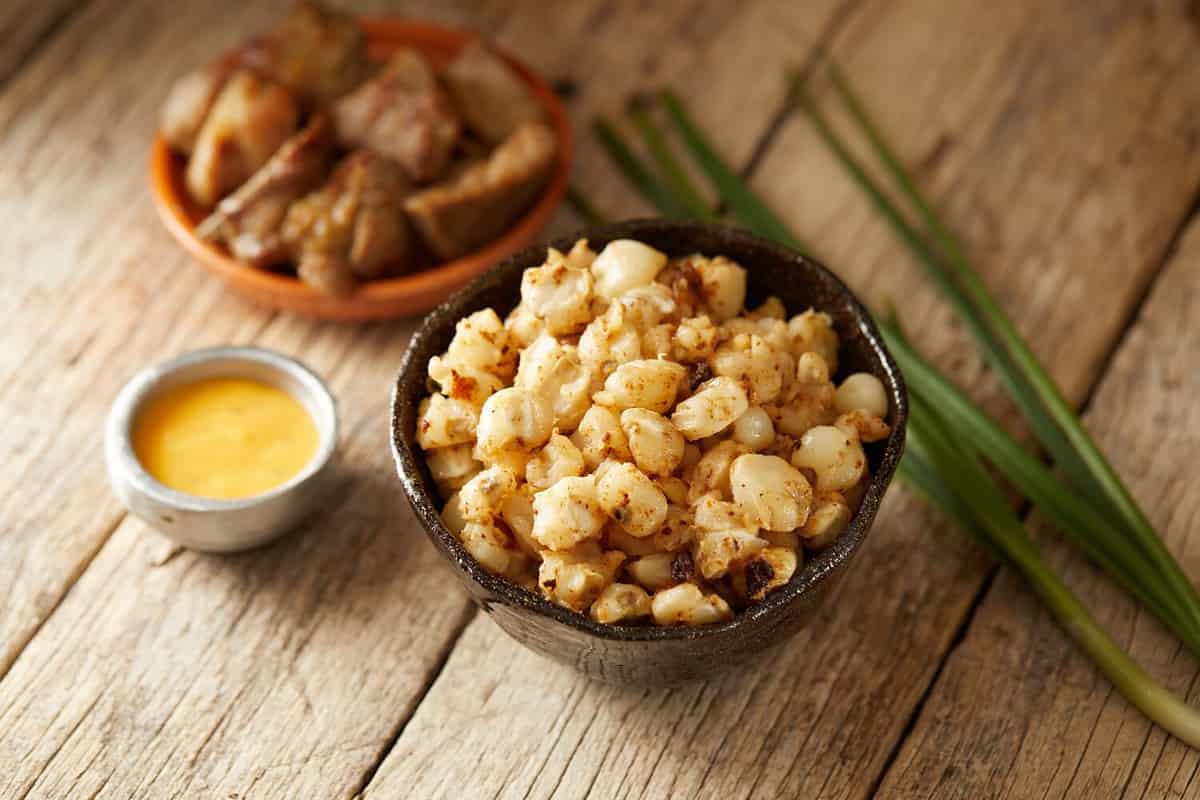 Mote sucio, a typical ecuadorian side dish made of hominy and pork rind. It’s served on a black bowl and with a traditional atmosphere.