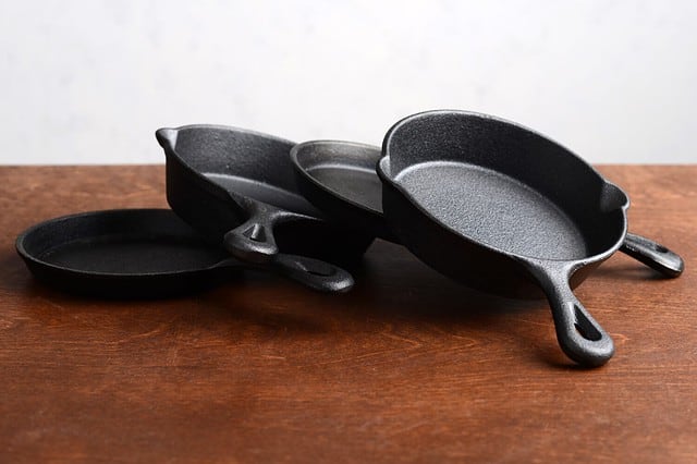 pile of cast iron skillets on old wood table