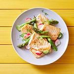 Top view of palatable grilled tilapia fish with cut vegetables served on plate on wooden table