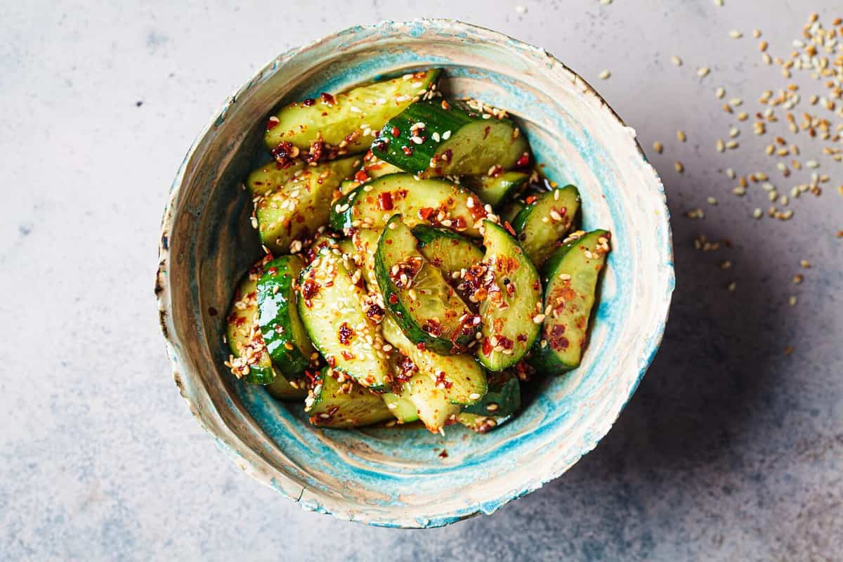 Chinese smashed cucumber salad with chili peppers and sesame seeds, top view.