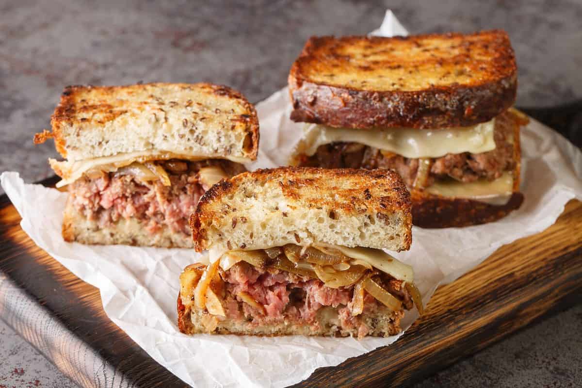 patty melt sandwich is a variant of the classic American cheeseburger using crispy bread, cheese, and tender onions closeup on the wooden board on the table. Horizontal