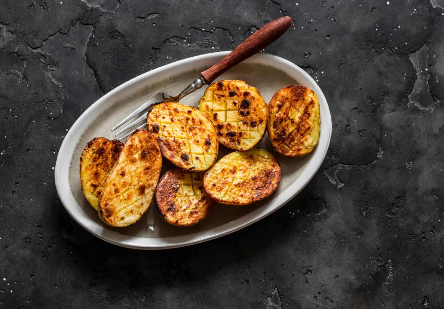 Barbecue grilled potatoes on a dark background top view