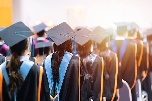 Rearview of university graduates wearing an academic gown on commencement day. Education stock photo