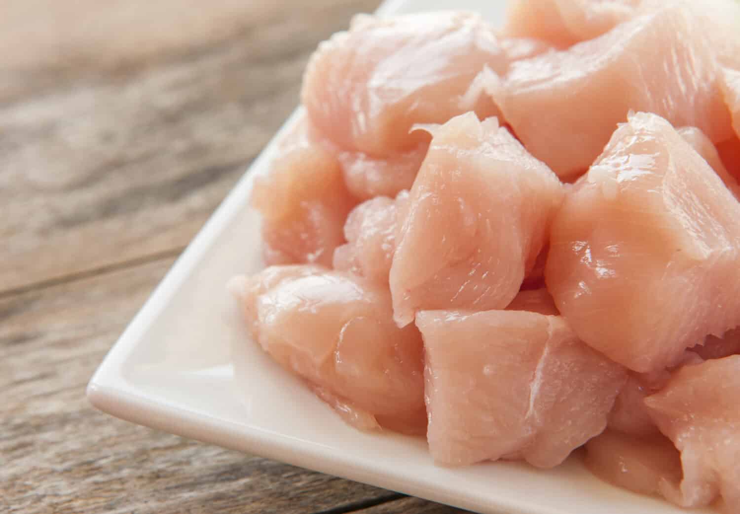 Raw chicken small pieces close up on wooden background