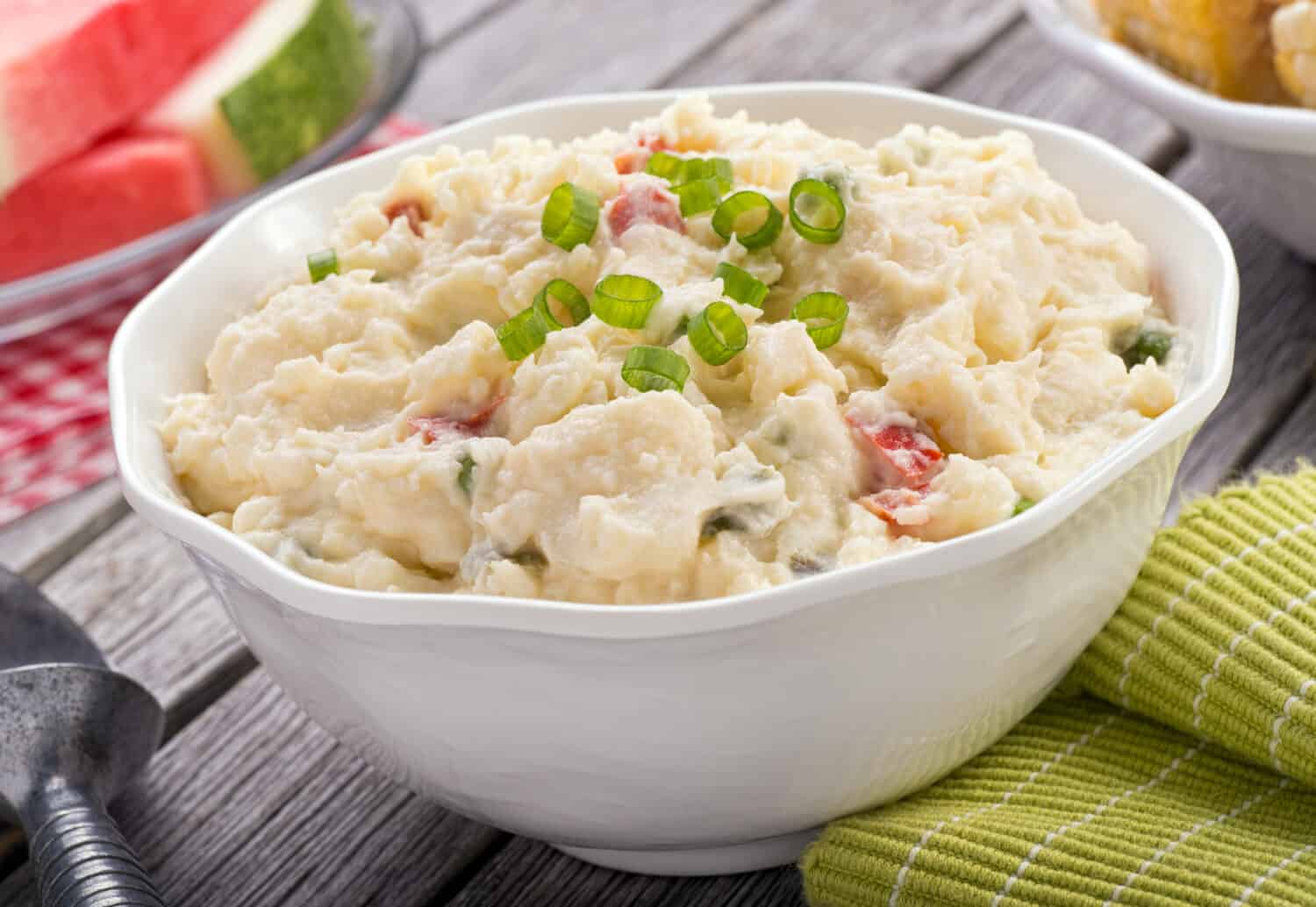 A delicious homemade creamy potato salad on a rustic picnic table.