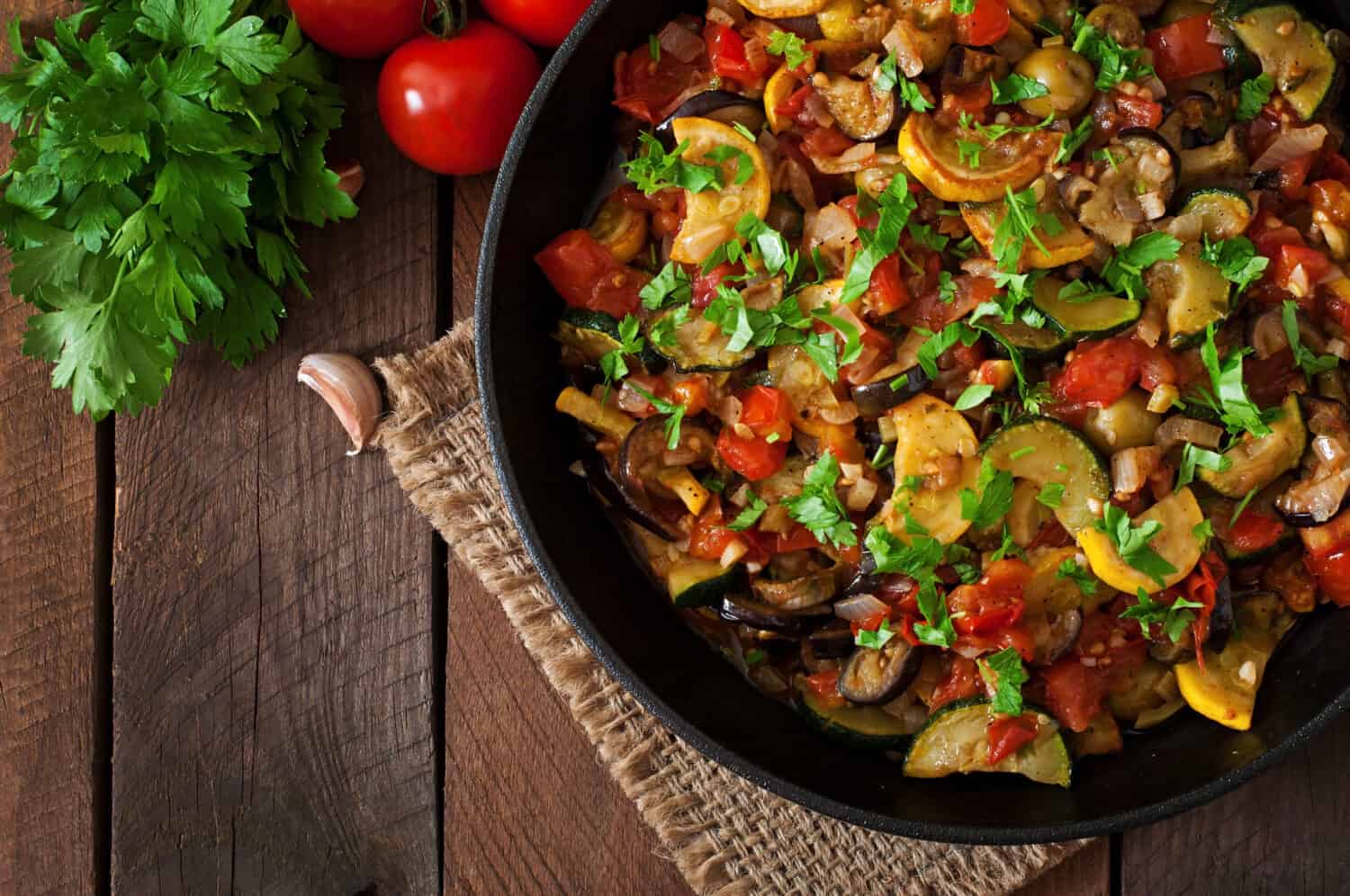 Vegetable Ratatouille in frying pan on a wooden table. Top view