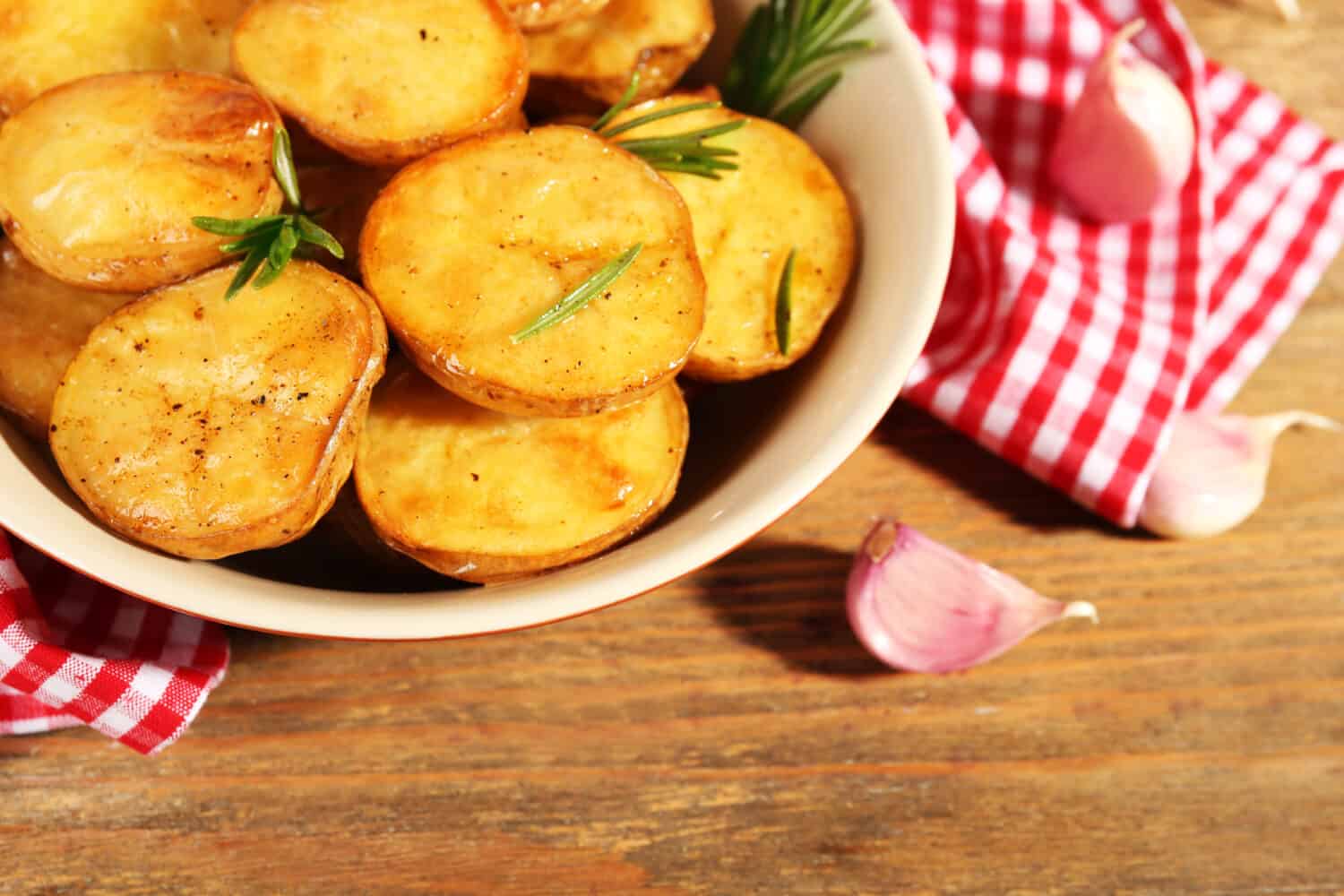 Delicious baked potato with rosemary in bowl on table close up