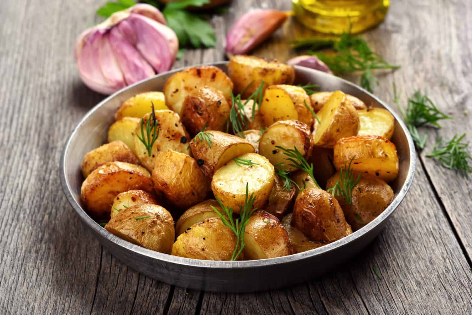 Roasted potato with dill on wooden background