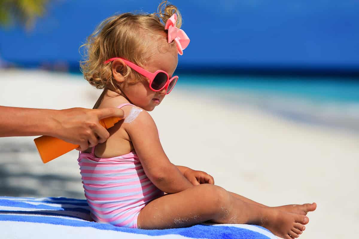 mother applying sunblock cream on daughter shoulder