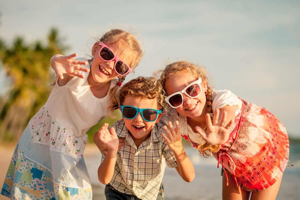 Happy children playing on the beach at the day time. Concept of happy friendly sister and brother.