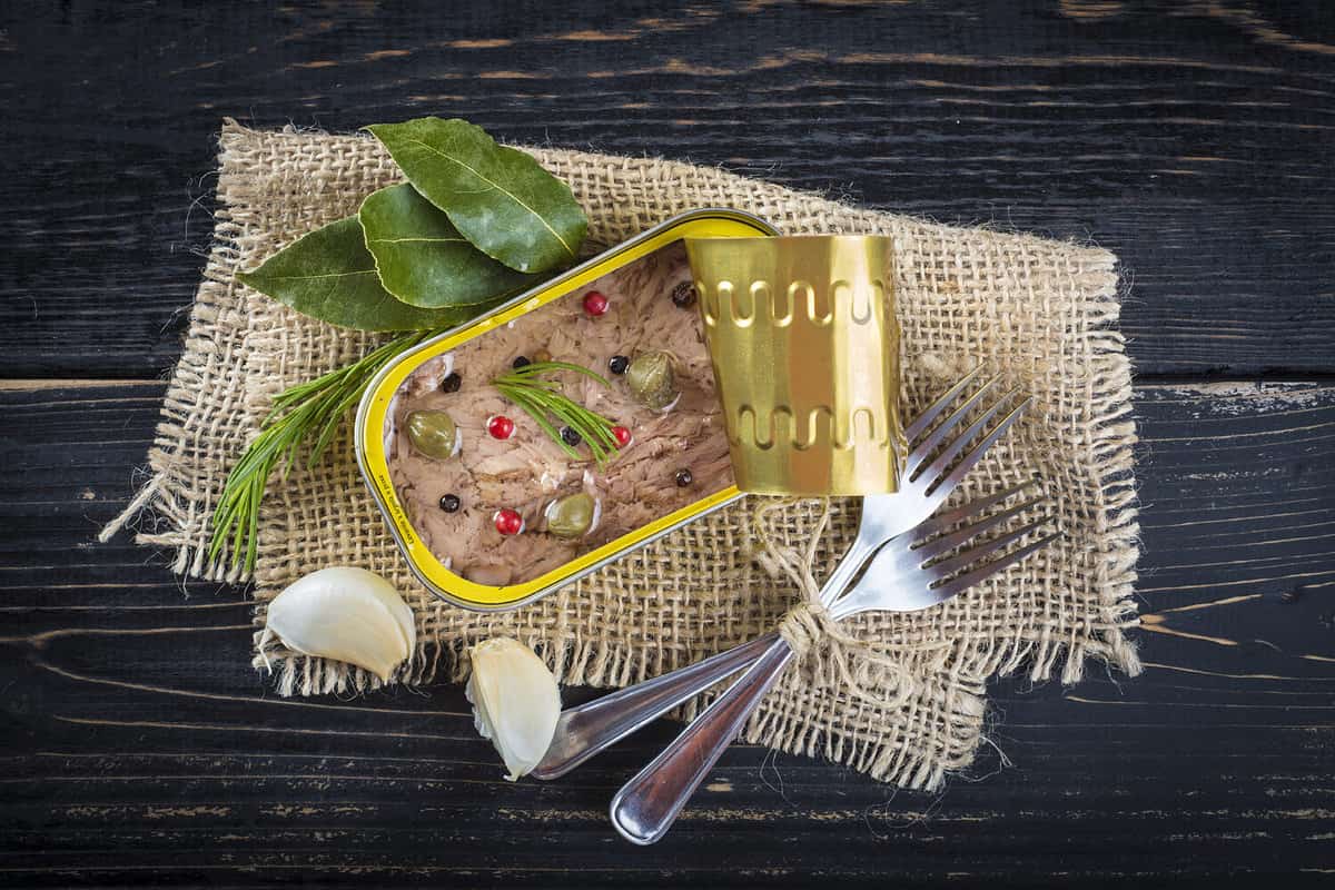 Light tuna in olive oil canned dressed with herbs and spices on a burlap and a wooden background