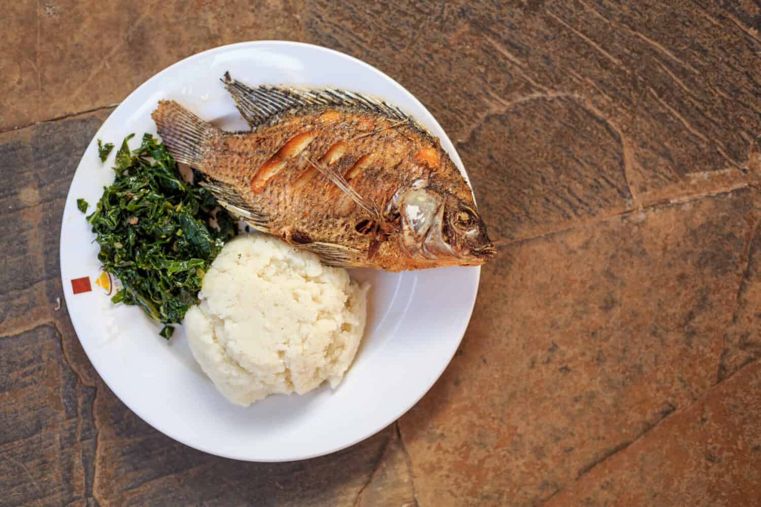 Traditional East African food - ugali, fish and greens