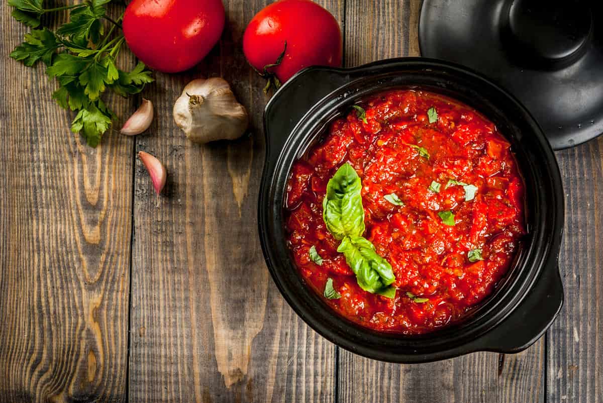 Basic Italian tomato sauce marinara for pasta. In a saucepot pan with ingredients on a wooden table. Top view copy space