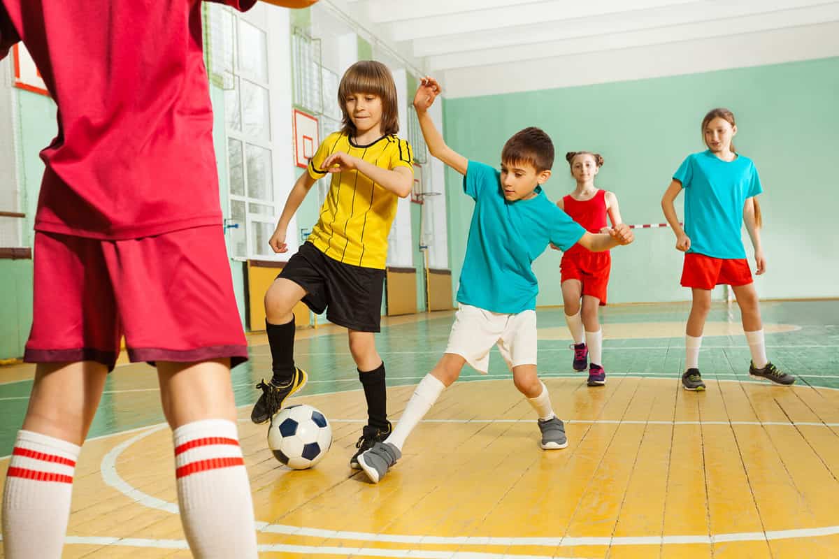 Children playing football in school gymnasium