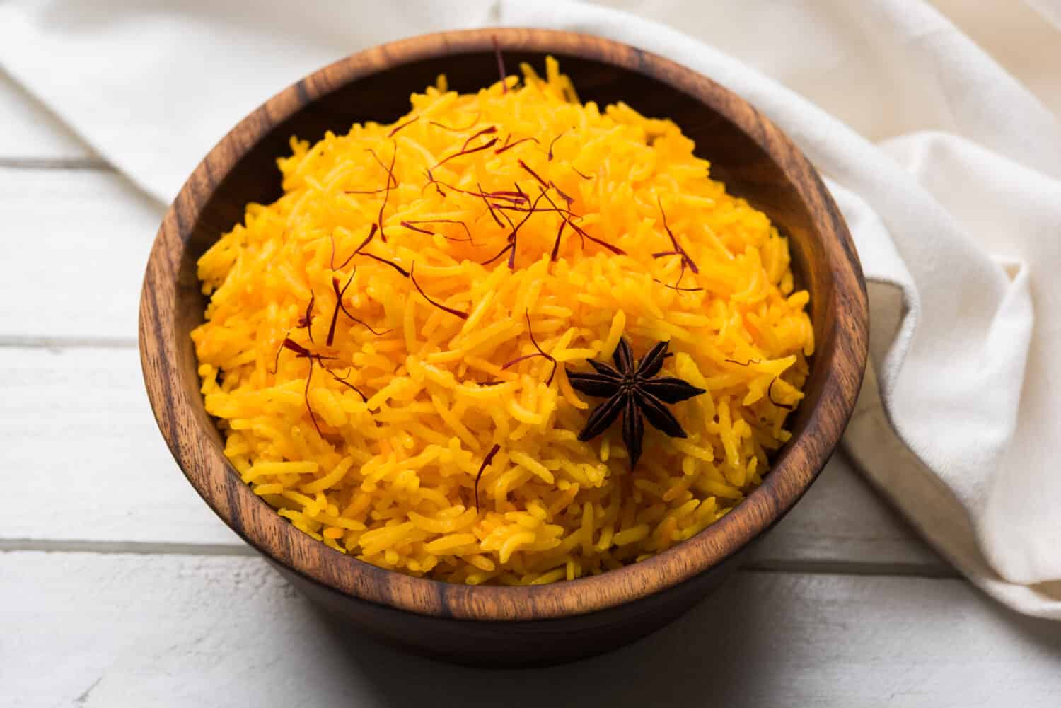 Saffron rice or Kesar chawal / bhat, served in a white ceramic bowl, selective focus