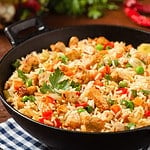 Fried rice with chicken. Prepared and served in a wok. Natural wood in the background. Front view.