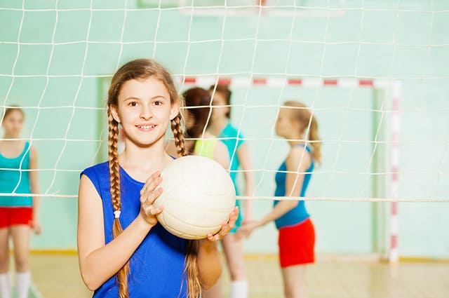 Teen girl with volleyball ball in sports hall