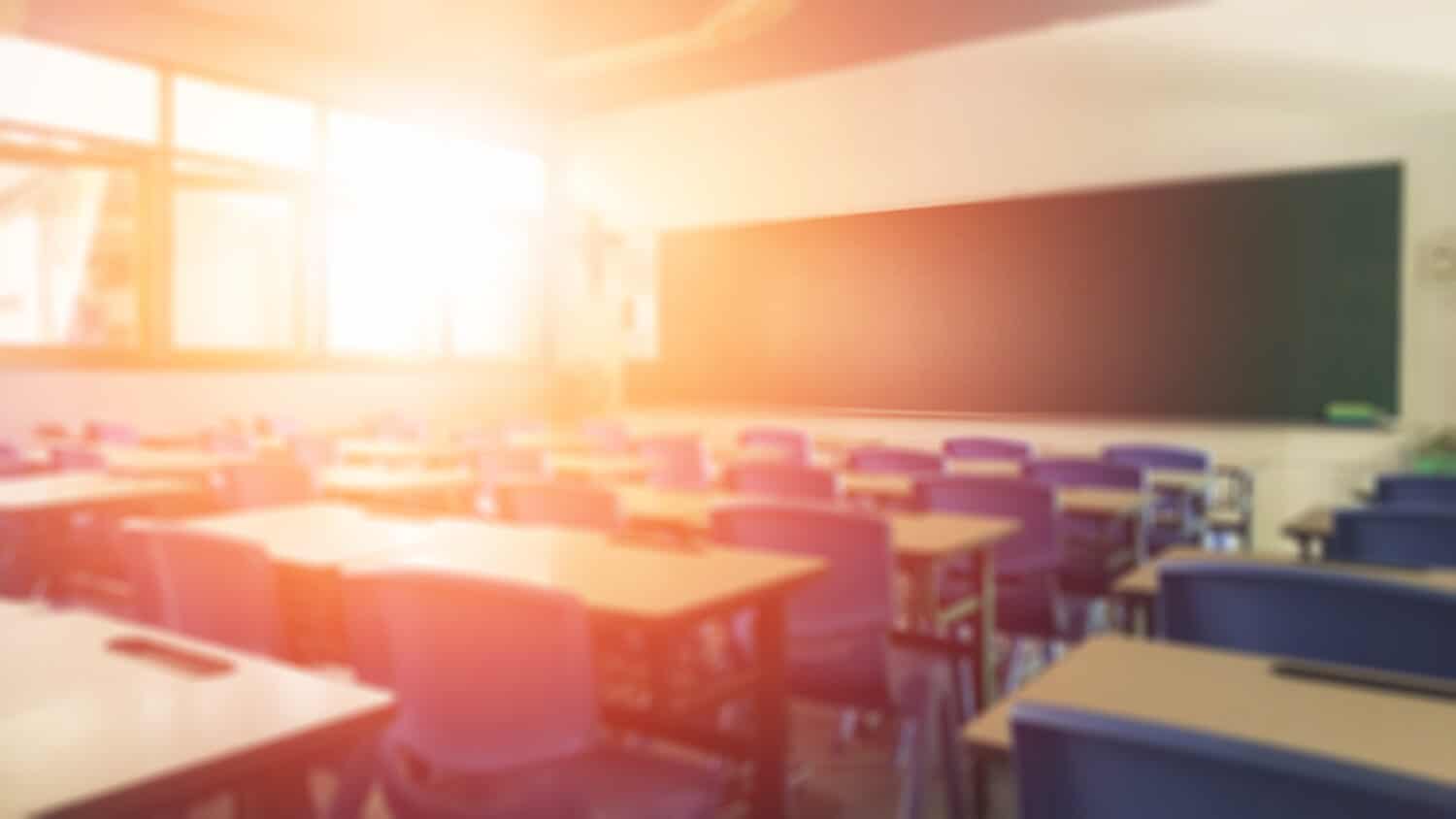 Back to school concept. Classroom in blur background without young student; Blurry view of elementary class room no kid or teacher with chairs and tables in campus.