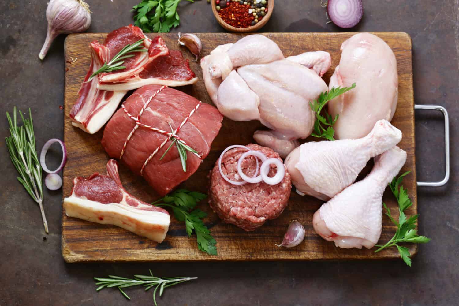 raw meat assortment - beef, lamb, chicken on a wooden board