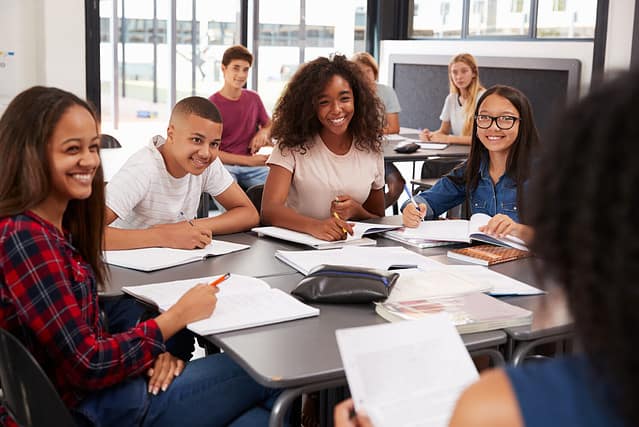 High school kids looking to teacher sitting at their desk