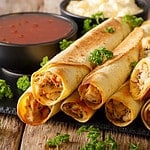 Baked taquitos with chicken and cheese close-up on the table. horizontal