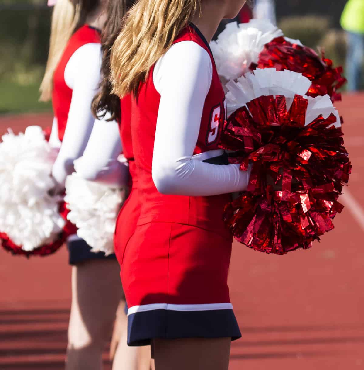 Cheerleaders paying attention to the football game while cheering for the home team at a local high school.