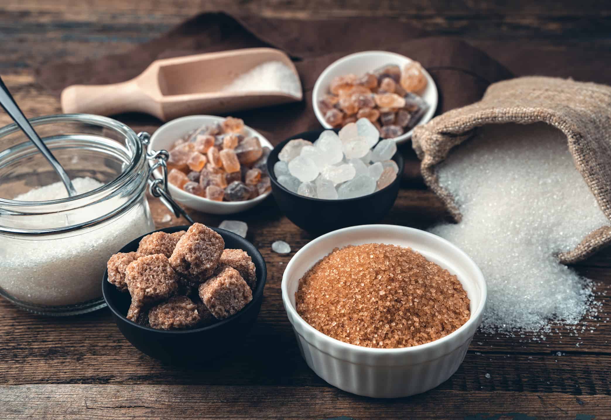 Many different types of sugar on a wooden background. Side view. Culinary background with vintage tinting. The concept of food products.